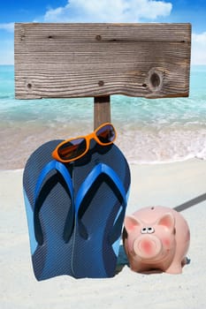 Piggy bank,flips flops and empty wooden sign on the beach