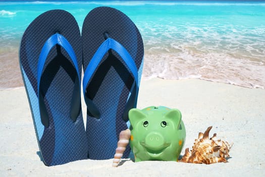 Piggy bank,flips flops and mussels on the beach
