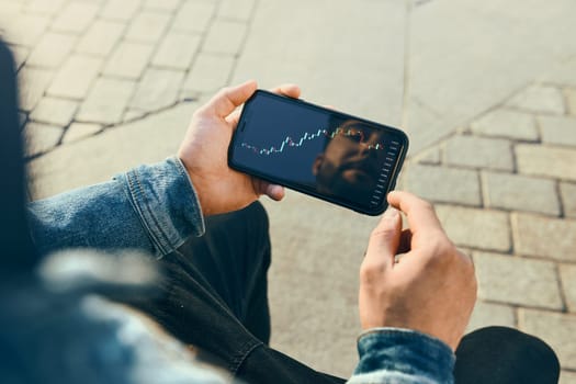 Person investing trading on stock cryptocurrency market using investing application on smartphone. Stock market investment in hand. Trader holding mobile phone looking at candle chart