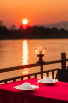 Dinner at riverside during sunset. Table and plates serving