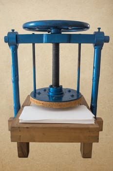 Screw bookbinding press over wooden stand. Isolated over old paper background