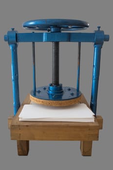 Screw bookbinding press over wooden stand. Isolated over grey background