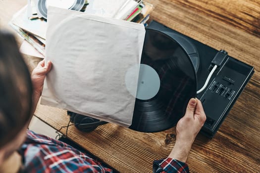 Man listening to music from vinyl record. Playing music from analog disk on turntable player. Enjoying music from old collection. Relaxing at home. Retro and vintage. Music passion