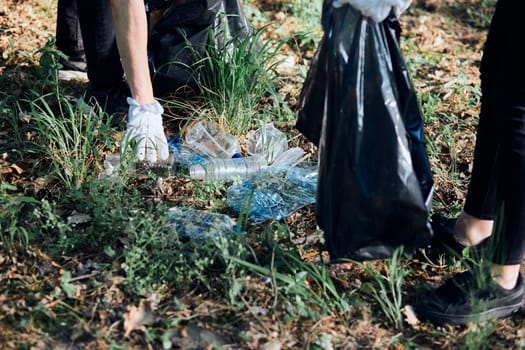 Young man and woman cleaning up a forest. Volunteers picking plastic waste to bags. Concept of plastic pollution and too many plastic waste. Environmental issue. Environmental damage. Responsibility for environment. Real people, authentic situations