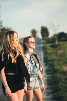 Teenage smiling happy girls having fun walking outdoors, hanging, spending time together on summer day