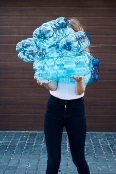 Young woman throwing out empty used plastic water bottles into trash bin. Collecting plastic waste to recycling. Concept of plastic pollution and too many plastic waste. Environmental issue