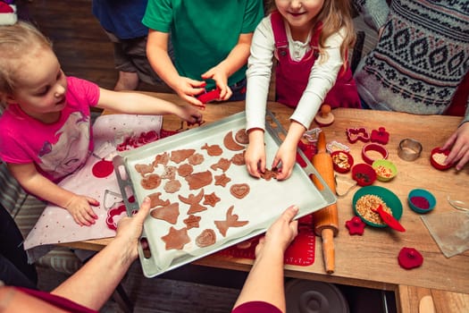 Baking Christmas cookies. Christmas gingerbread cookies in many shapes decorated with colorful frosting, sprinkle, icing, chocolate coating, toppers, put on table. Baking traditional cookies. Family celebrating Christmas. Baking at home. Baked sweet cookies. Coating with frostings. Colouring cookies. Decorating baked cookies. Decoration and design of food. Flat top-down composition. Sweet dessert food. Putting a frost, frosting gingerbread. Shot from above