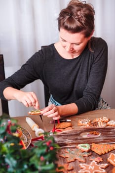 Woman decorating baked Christmas gingerbread with frosting