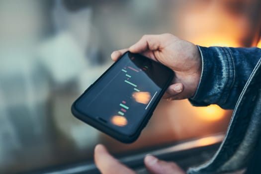 Person investing trading on stock cryptocurrency market using investing application on smartphone. Stock market investment in hand. Trader holding mobile phone looking at candle chart
