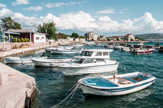 Many boats moored to the pier and shore. Town in the distant