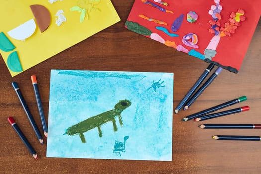 Preschooler pictures done at school. Kids drawings of animals done with crayons and paper. Concept of early education