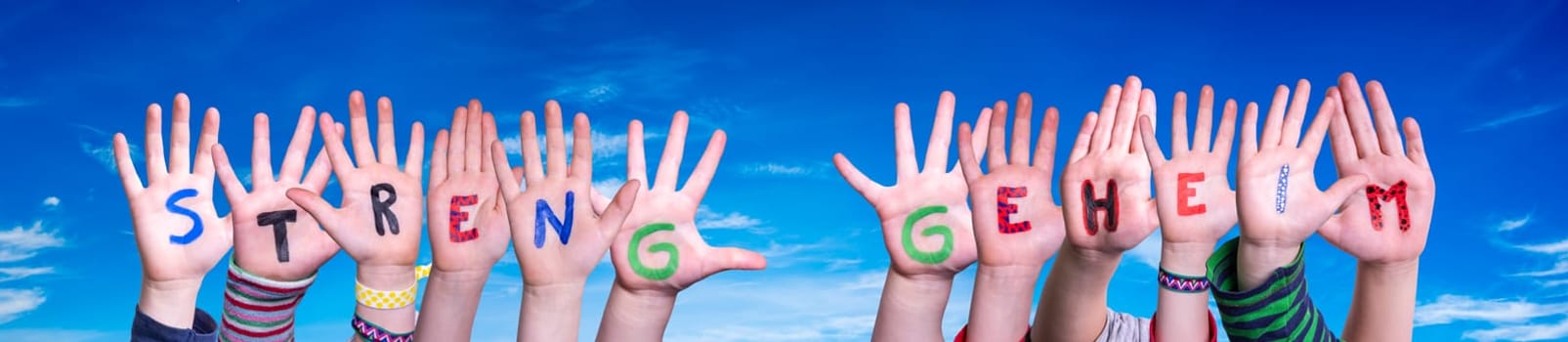 Children Hands Building Colorful German Word Streng Geheim Means Top Secret. Blue Sky As Background.