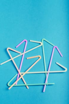 Heap of plastic drink straws scattered over blue background. Collecting plastic waste to recycling. Concept of plastic pollution and too many plastic waste. Copy space at the top