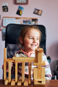 Little girl preschooler playing with wooden blocks toy building a tower. Concept of building a house