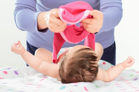 Mom dressing her little baby girl