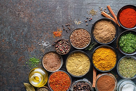 Colorful herbs and spices for cooking meal. Indian and Asian spices On grey stone background. Top view.