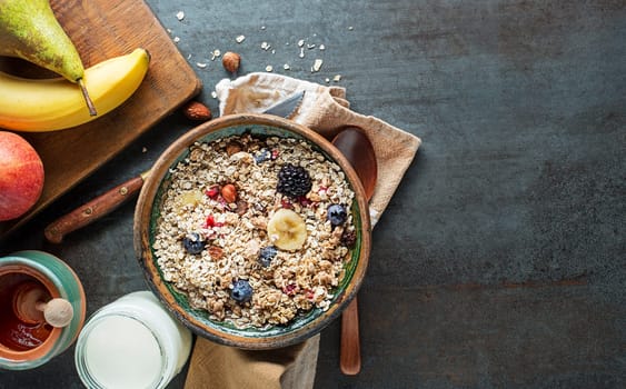 A bowl of dry granola and muesli served with fresh fruit. Oatmeal breakfast. Healthy food, diet. Top view.