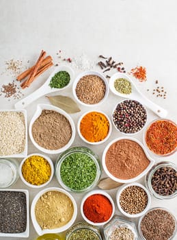 Colorful herbs and spices for cooking dishes. Indian and asian spices on white stone background. Top view.