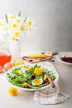 Dandelion salad with eggs, potato and beans on bright table background