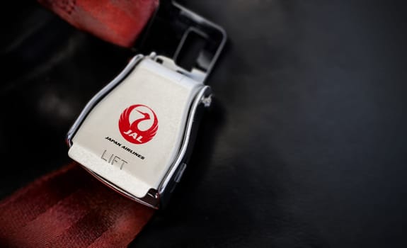 Tokyo, JP Jan 2023: detail of the buckle of the seat belt with Japan Airlines logo on an empty seat. JAL is the Japan flag carrier. Illustrative editorial.