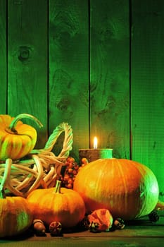 Halloween pumpkins in rattan basket in front of an old weathered wooden wall in extraordinary green Halloween light
