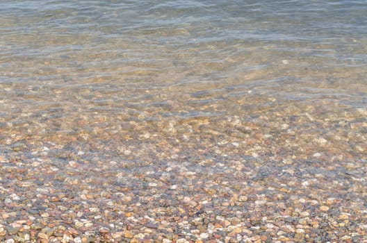 Shoreland,overlooking small pebbles in a clear river.
