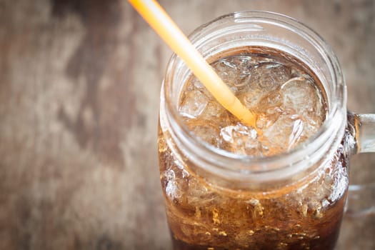 Glass of cola with ice on wooden table, stock photo