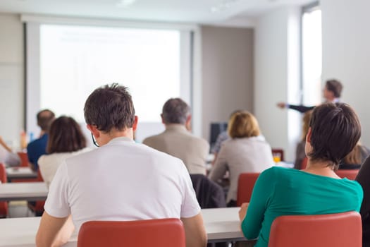 Speaker Giving a Talk at Business Meeting. Audience in the conference hall. Business and Entrepreneurship. Copy space on white board.