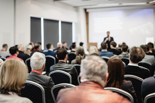 Speaker giving a talk in conference hall at business event. Rear view of unrecognizable people in audience at the conference hall. Business and entrepreneurship concept