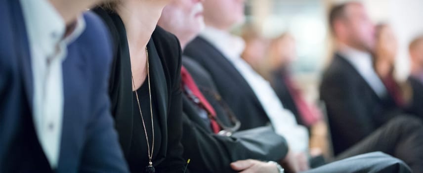 Row of unrecognizable business people sitting in conference hall at business event. Audience at business seminar. Business and Entrepreneurship concept.