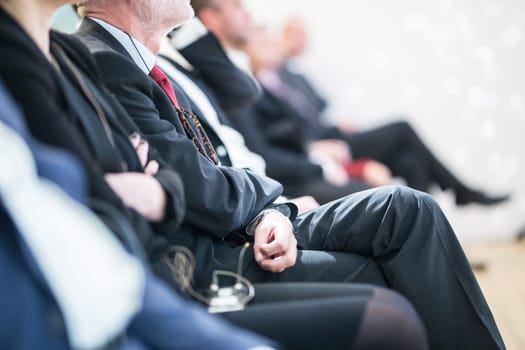 Row of unrecognizable business people sitting in conference hall at business event. Audience at business seminar. Business and Entrepreneurship concept.