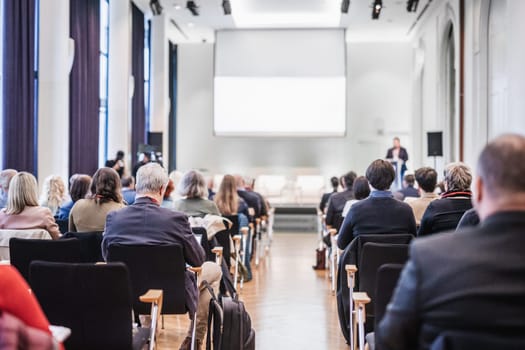 Speaker giving a talk in conference hall at business event. Rear view of unrecognizable people in audience at the conference hall. Business and entrepreneurship concept