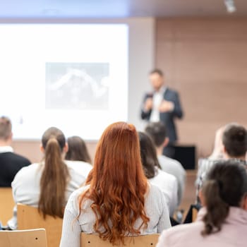 Speaker giving a talk in conference hall at business event. Rear view of unrecognizable people in audience at the conference hall. Business and entrepreneurship concept