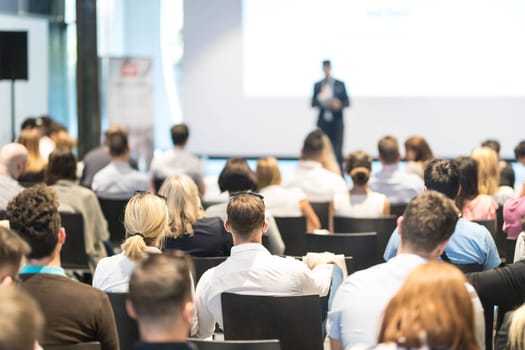 Speaker giving a talk in conference hall at business event. Audience at the conference hall. Business and Entrepreneurship concept. Focus on unrecognizable people in audience.