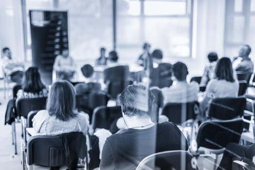 Round table discussion at Business convention and Presentation. Audience at the conference hall. Business and entrepreneurship symposium. Black and white blue toned image.