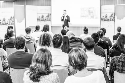 Speaker giving talk at business event. Audience at the conference hall. Business and Entrepreneurship concept. Focus on unrecognizable people in audience. Black and white.