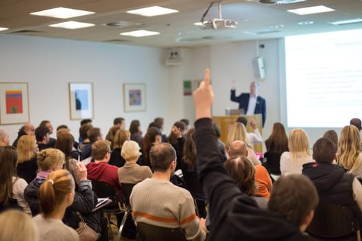 I have a question. Group of people sitting at the chairs in conference hall, raising their hands. Workshop at university. Business and Entrepreneurship event.