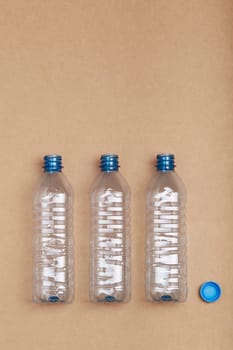 Empty plastic bottles put in a row, over cardboard background. Collecting plastic waste to recycling. Concept of plastic pollution and too many plastic waste. Copy space for text