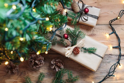 Christmas presents under a Christmas tree. Gifts wrapped in paper decorated with cones and pine twigs put on wooden floor. View from above. Copy space for text at top of image