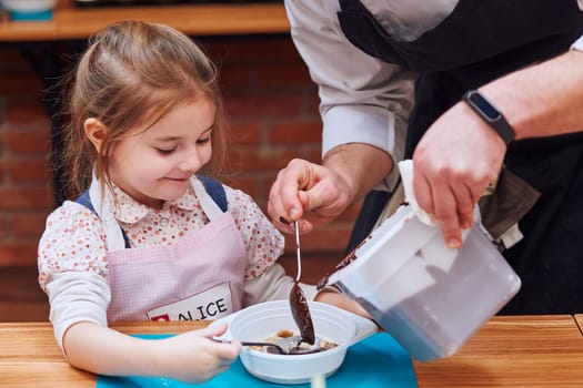 Chef adding hot melted chocolate with cocoa to container. Kid taking part in baking workshop. Baking classes for children,  aspiring little chefs. Learning to cook. Combining and stirring prepared ingredients. Real people, authentic situations
