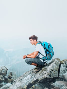 Boy with backpack sitting on peak in the Tatra Mountains, resting during hiking. Copy space in the top