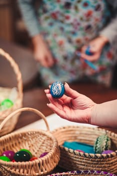 People decorating the Easter eggs by scratching patterns on dyed eggs. Traditional Easter time, spring time, new beginnings. Candid people, real moments, authentic situations