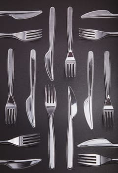 Plastic forks and knives scattered over red background. Collecting plastic waste to recycling. Concept of plastic pollution and too many plastic waste. Copy space at the top
