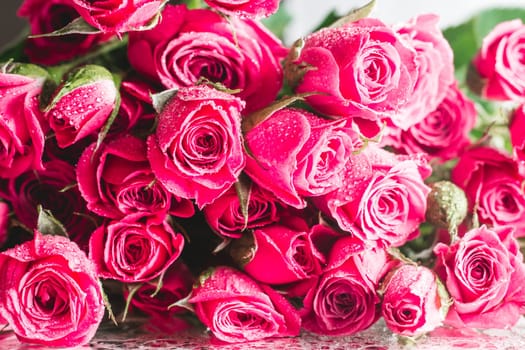 Blurred creative background of pink rose flowers. Partially defocused roses on glossy surface with water drops