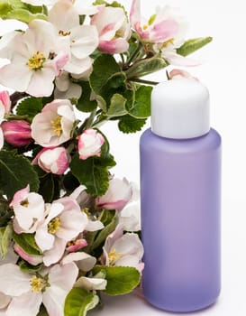 Lilac cosmetic bottle with pear flowers on a white background. Natural organic cosmetics concept