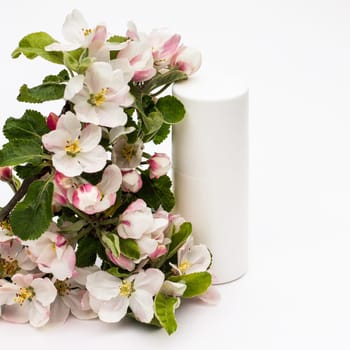 White cosmetic bottle with pear flowers on a white background. Natural organic cosmetics concept