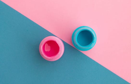 Jars with blue and pink paint on a diagonal background. Top view