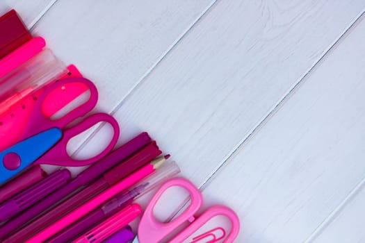 Pink school supplies on a white wooden background. Top view. Copy space. Education and back to school concept.
