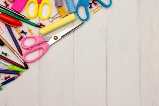 Coloured school supplies on a white wooden background, . Top view. Copy space. Education and back to school concept.