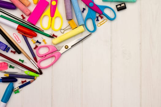 Coloured school supplies on a white wooden background, . Top view. Copy space. Education and back to school concept.